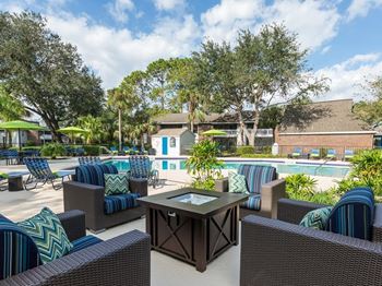 A sunny day at the poolside with wicker chairs and tables.